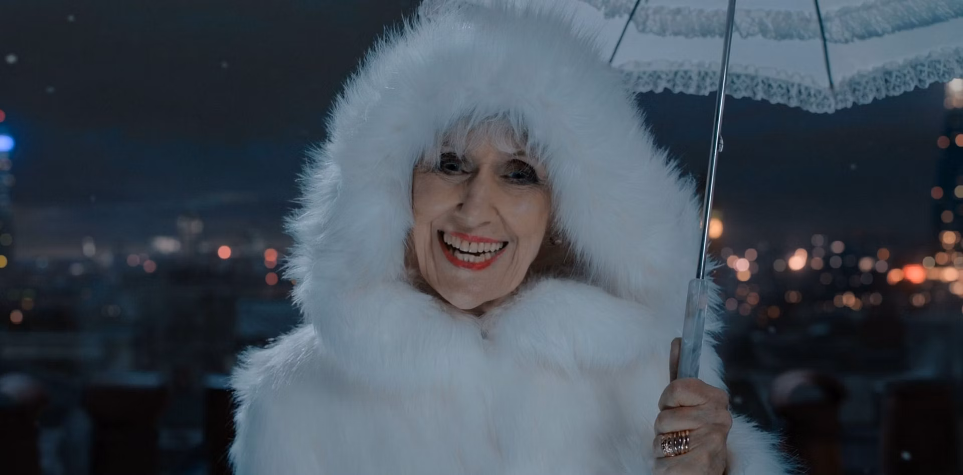 Miss. Flood dressed in a snow white cloak, with a fur hood and a matching umbrella.